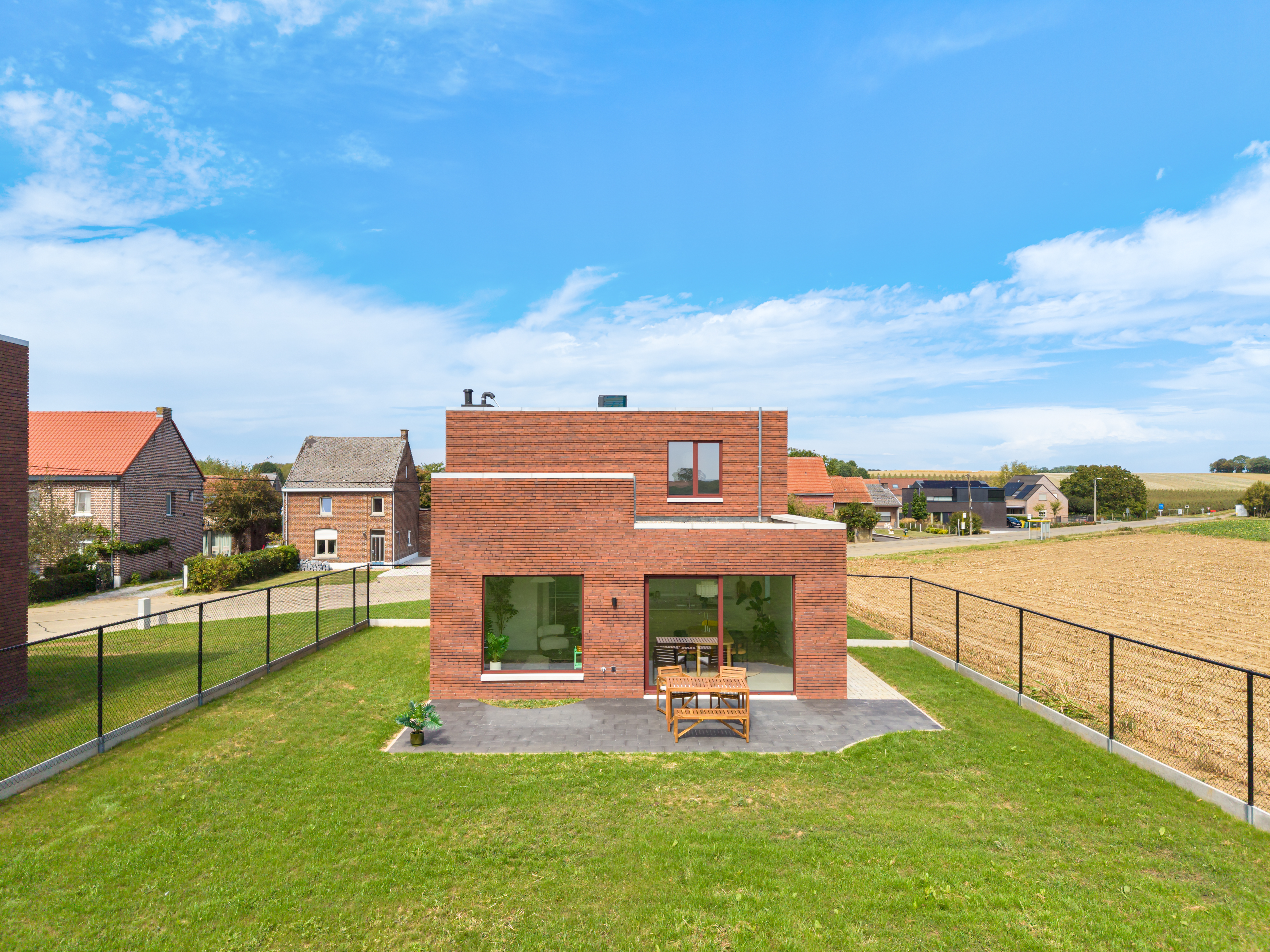 Luchtbeeld van de woning met tuin, terras en omliggende velden