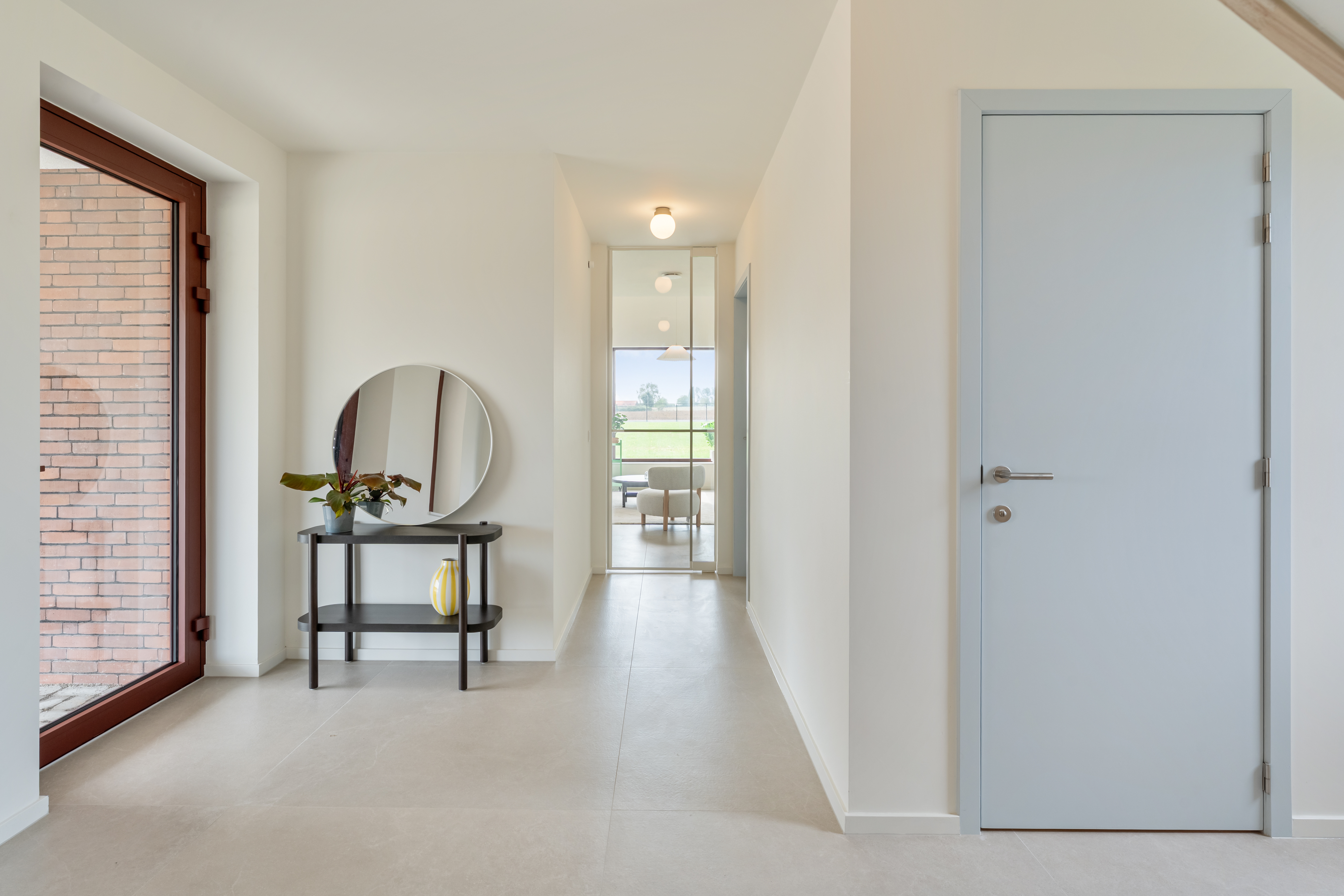 Inkomhal met keramische vloer, zichtbeton en doorkijk naar de leefruimte
