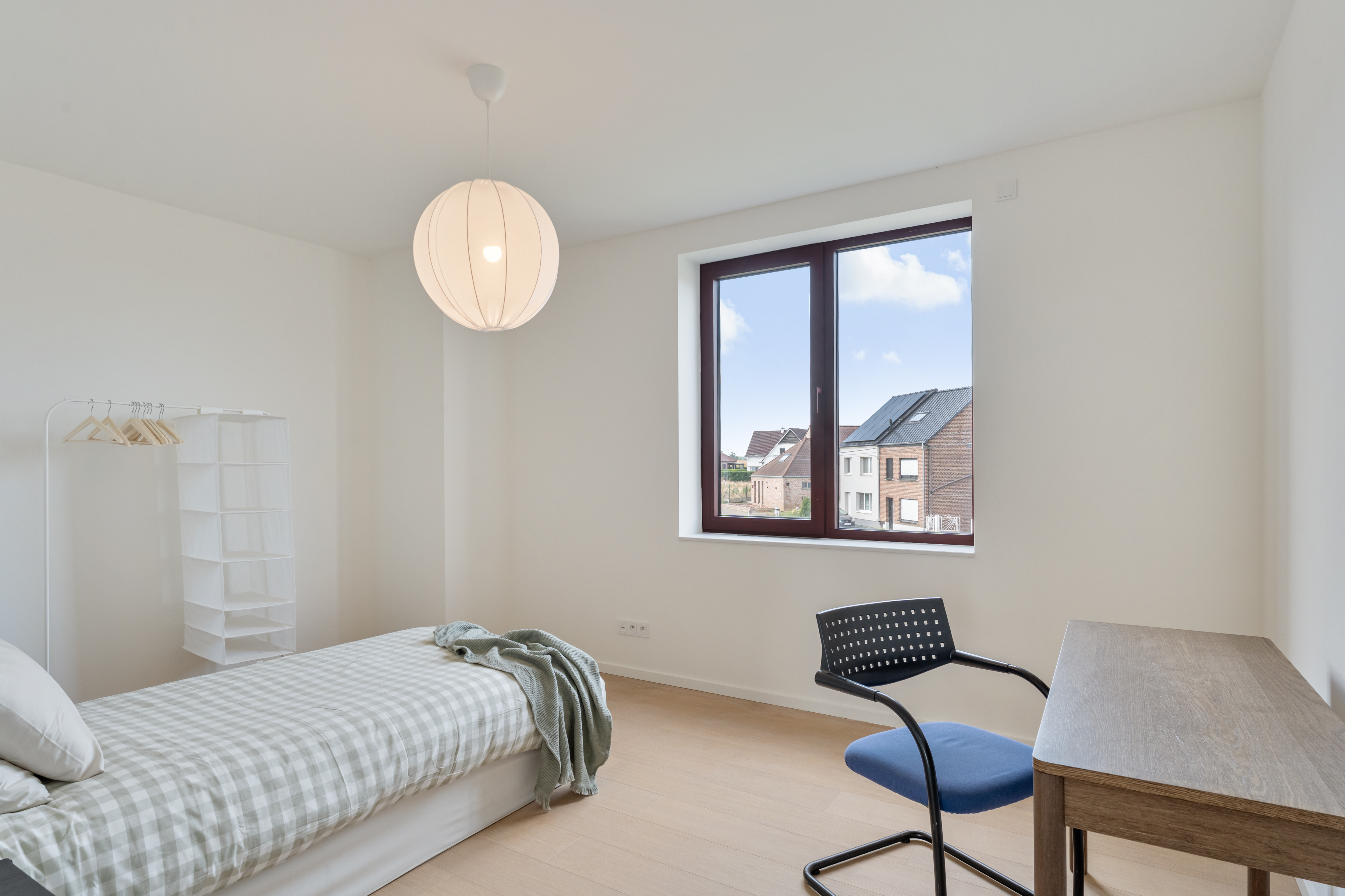 Slaapkamer met bureau en zicht op de straat