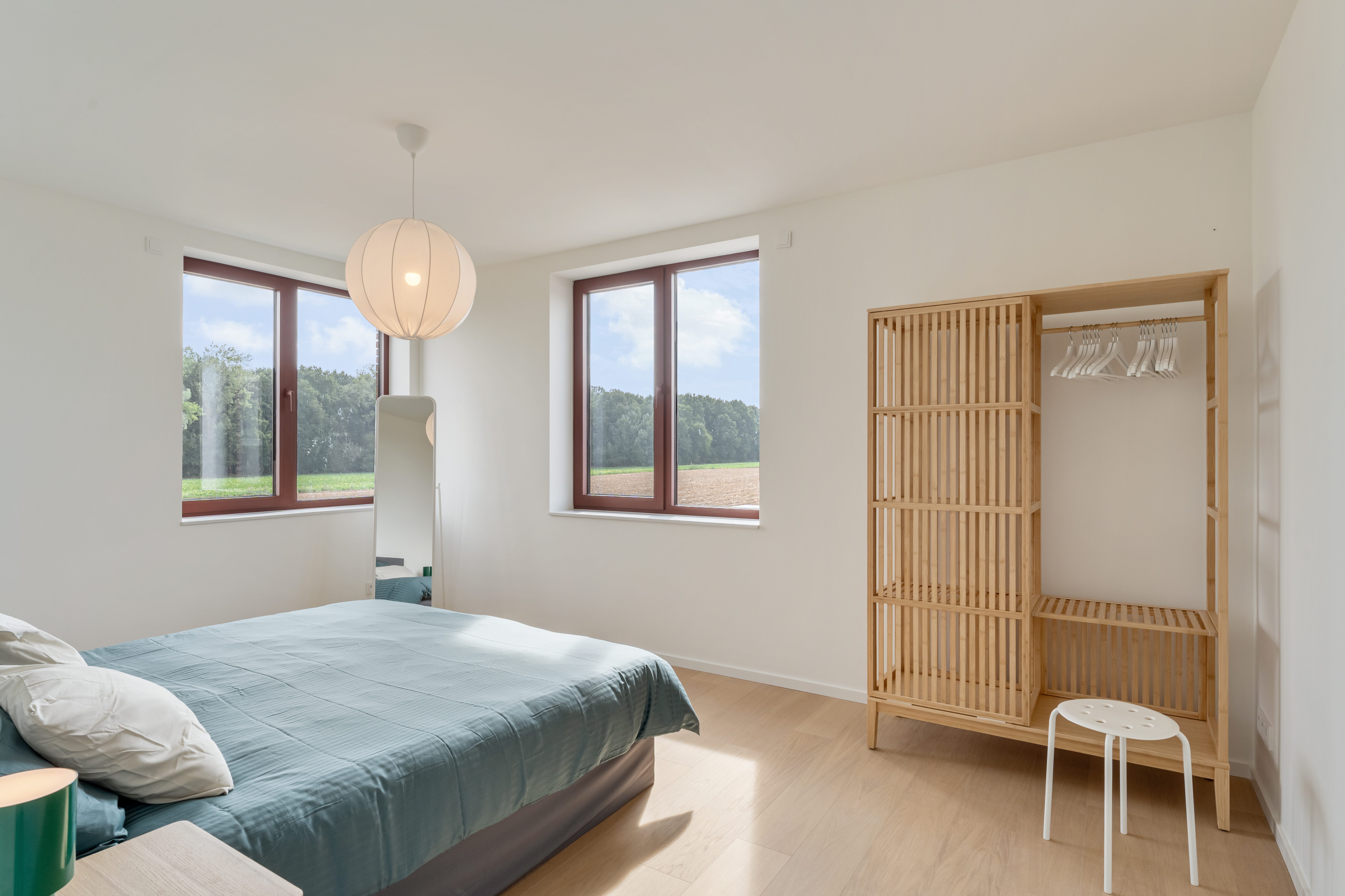 Slaapkamer met houten vloer, inbouwkast en zicht op de velden