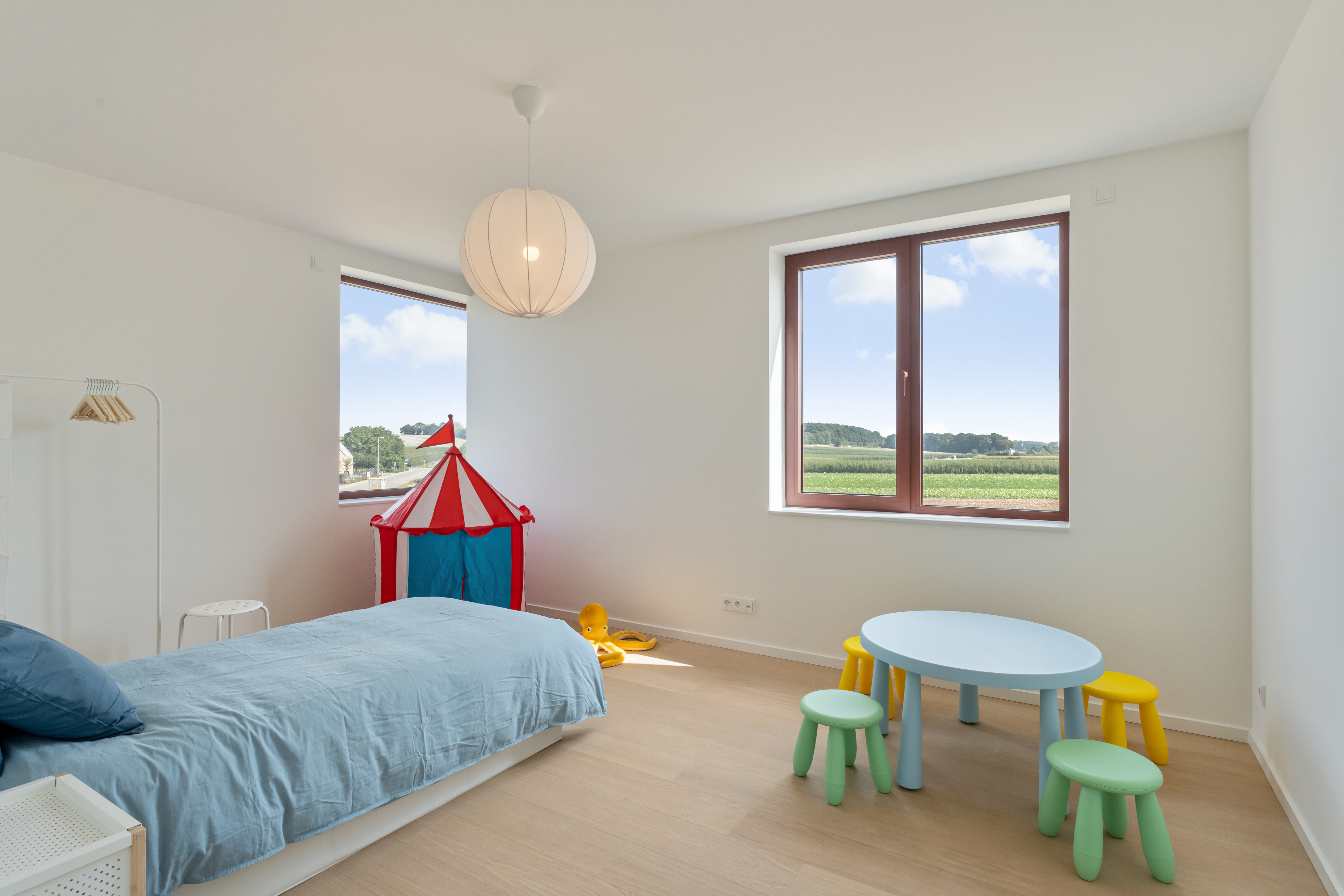 Kinderslaapkamer met speelhoek en zicht op de velden