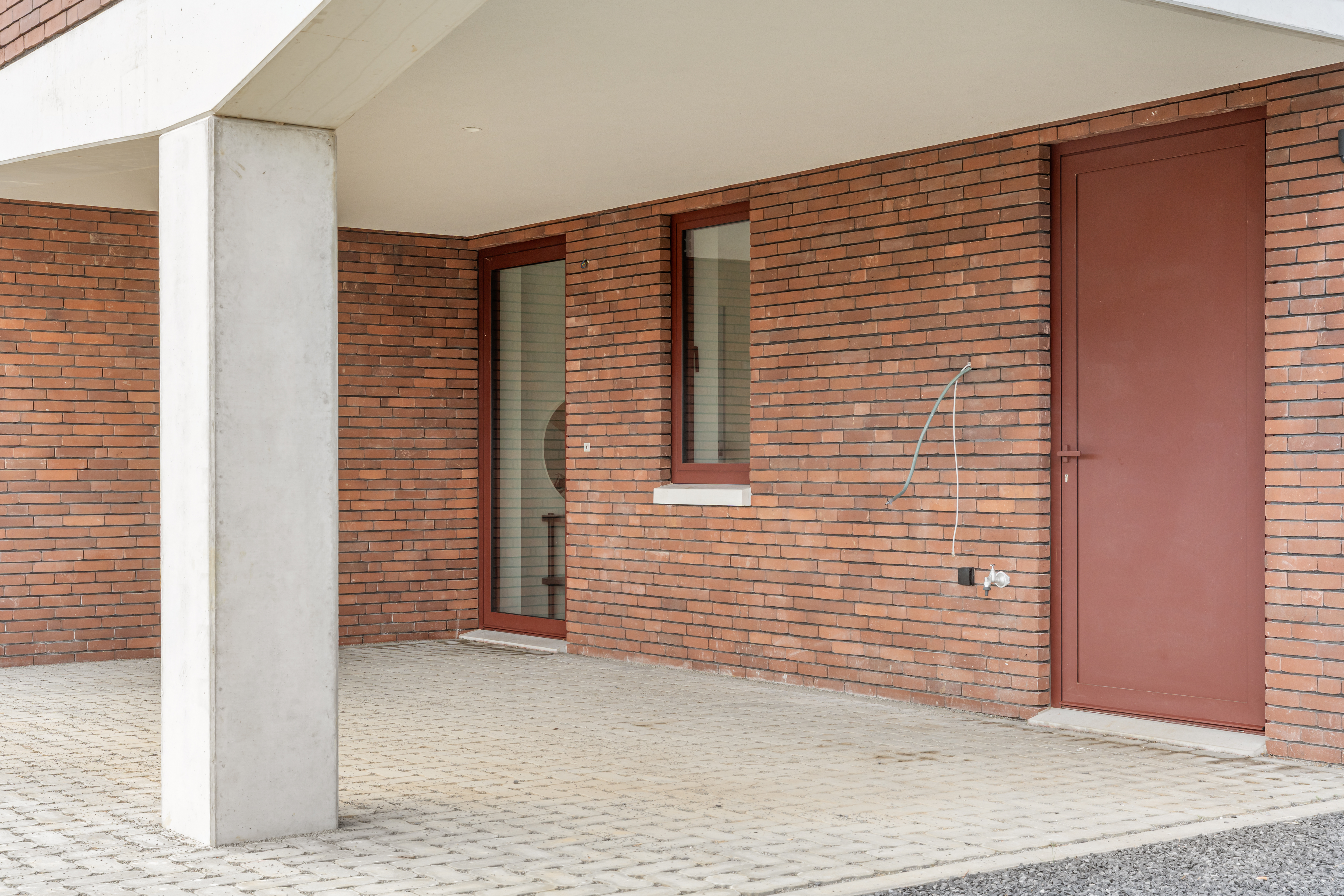 Inpandige carport met betonnen kolom, zijdeur en toegang tot de berging