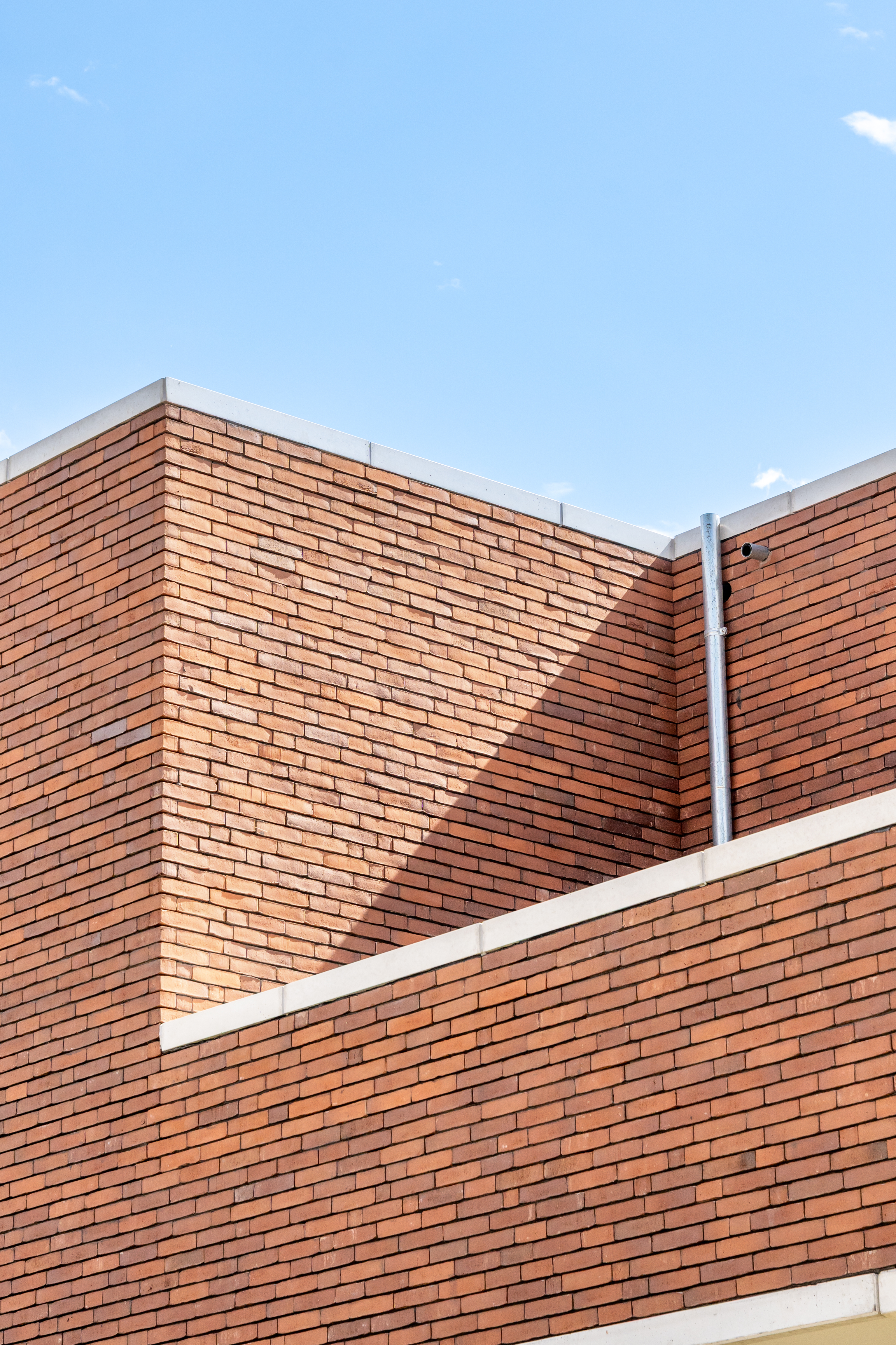 Detail van de roodbruine vormbaksteen met witte accenten in zichtbeton